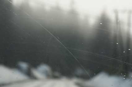 Damaged car window with scratches and cracks caused by improper tinting.